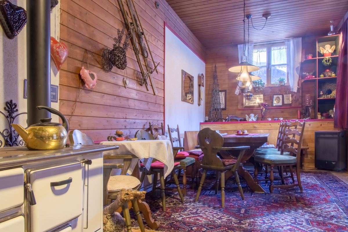 Urige Stube als gemeinsamer Aufenthaltsraum mit altem Kachelofen, Holztisch und Geweihschmuck