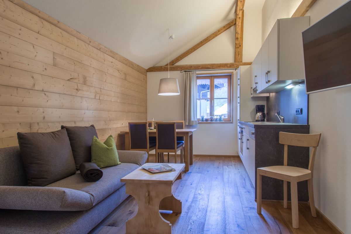 Wohnraum mit Sofa, Esstisch und Küchenzeile unter der Dachschräge